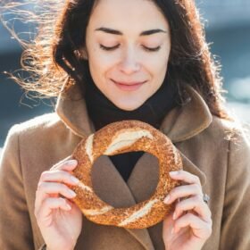 Beautiful woman holds a traditional Turkish simit in hands and wants to eat it